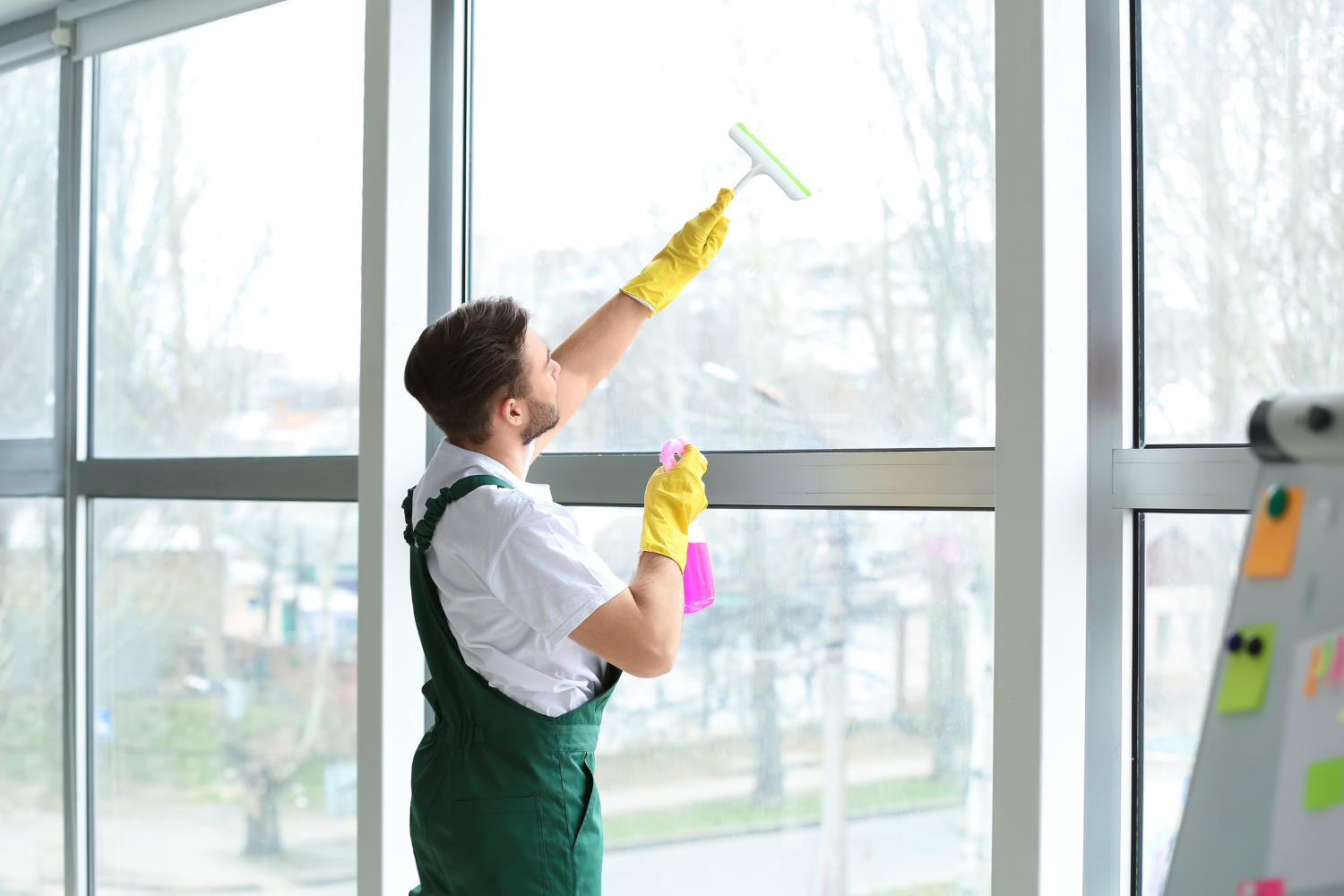 A person cleaning a modern vinyl window frame to extend its lifespan.