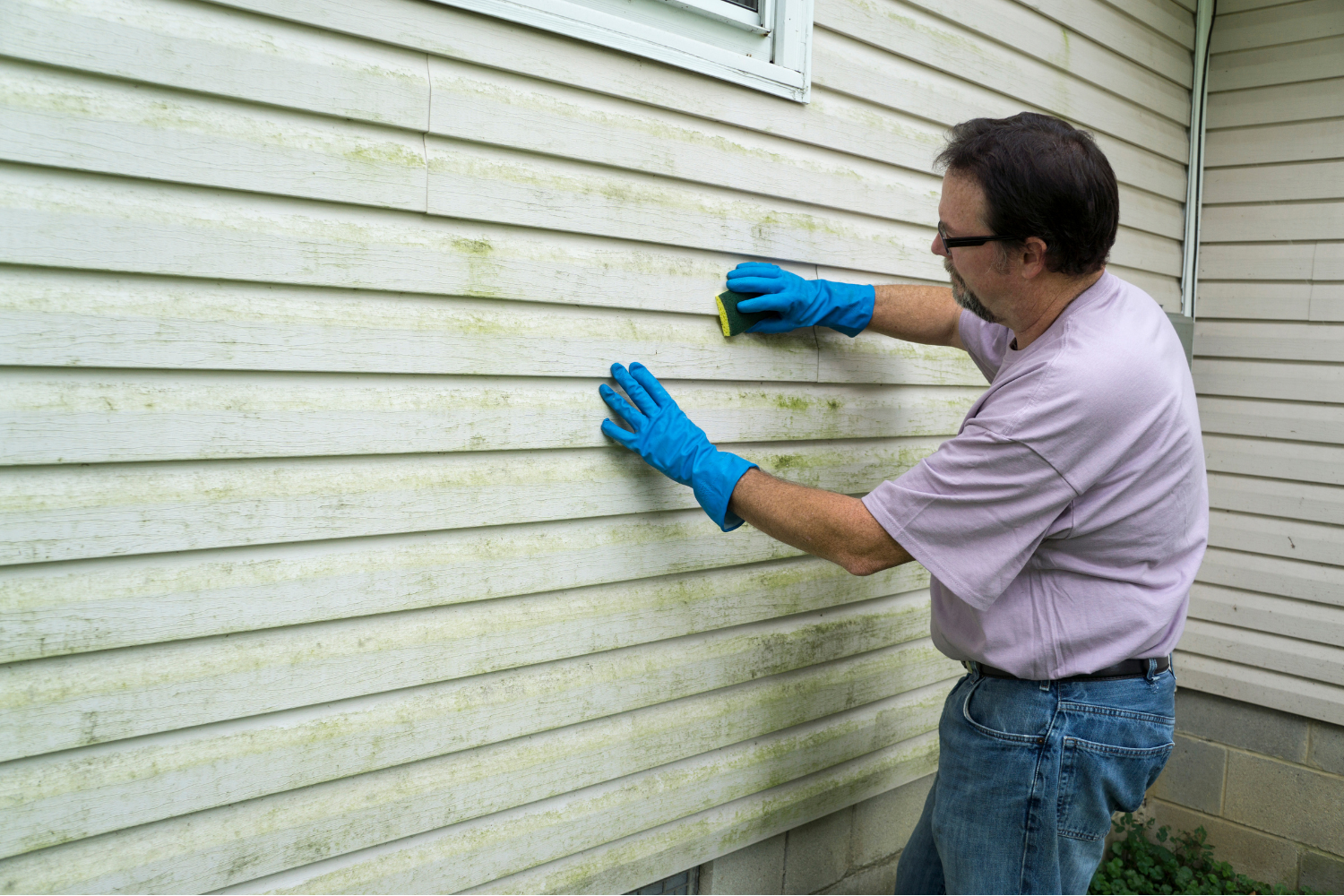 Photo of a person inspecting and maintaining painted vinyl siding