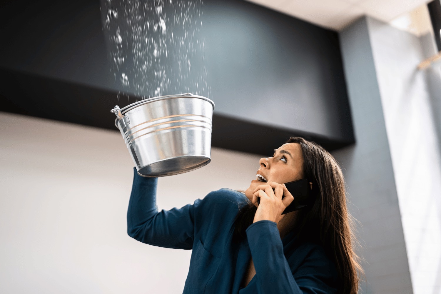 Person placing a bucket to collect water from a leaking roof