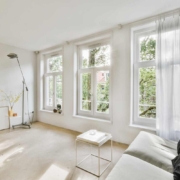 a living room with a couch and three windows