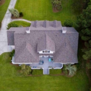 Aerial view of large home with new roof on beautiful property.