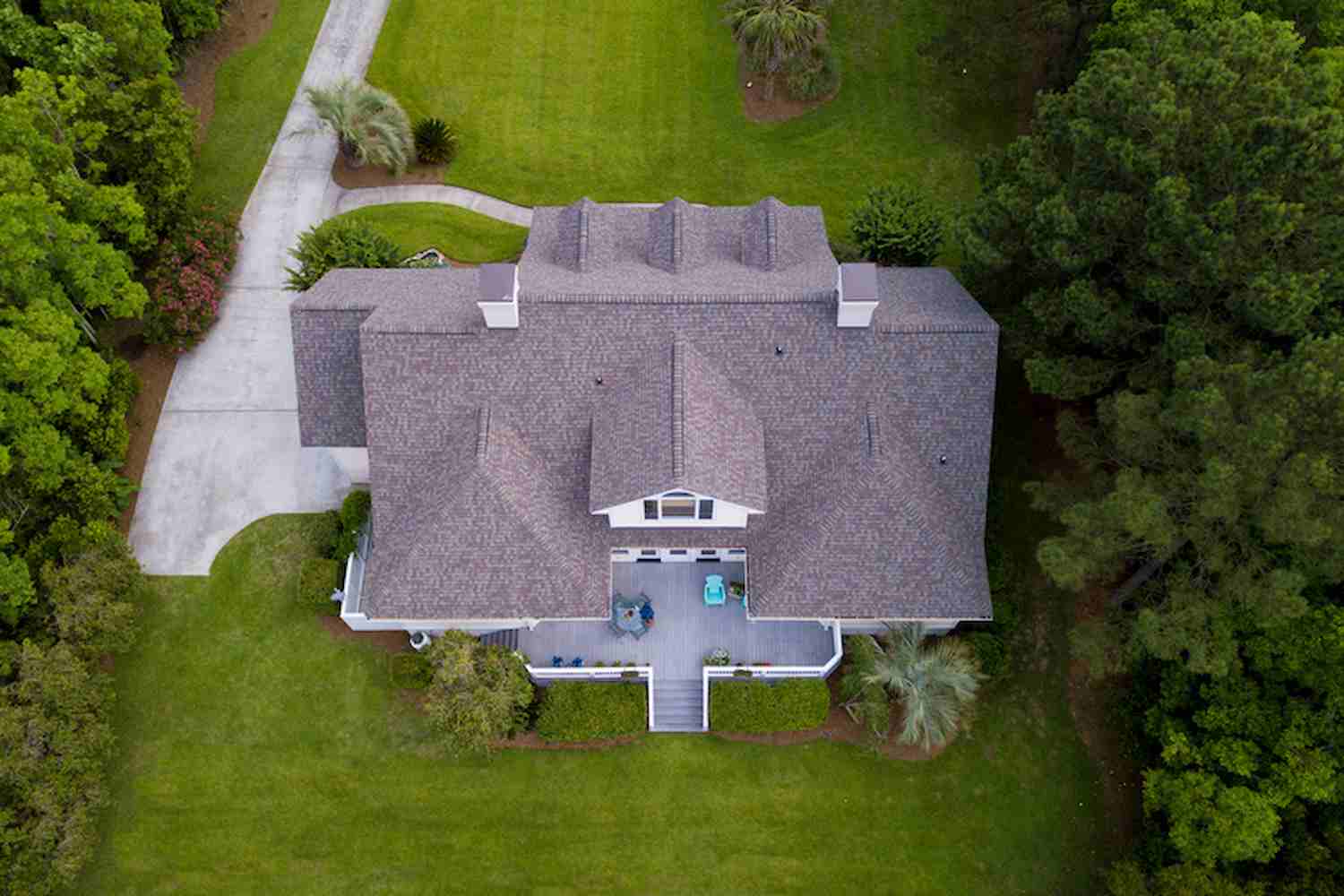 Aerial view of large home with new roof on beautiful property.