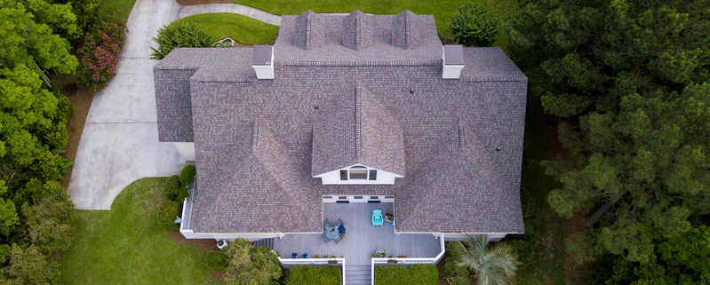 Aerial view of large home with new roof on beautiful property.