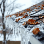 The image depicts clogged gutters filled with standing water and ice, leading to visible roof damage, such as sagging shingles and potential roof soft spots. This situation highlights the need for regular roof inspections and immediate attention to prevent costly repairs and maintain the structural integrity of the roofing system.